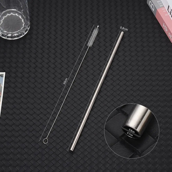 A set of reusable stainless steel drinking straws and a measuring tool are displayed on a dark surface.