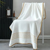 A white bath towel with gold stripes draped over a modern stand.