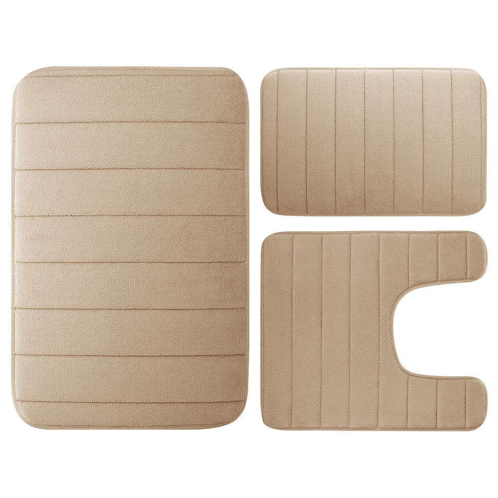 Ein Set aus drei beige Memory-Schaum-Badezimmerteppichen, darunter eine rechteckige Matte und zwei unregelmäßige Formen.