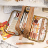 A tan pencil pouch filled with various pens and pencils rests on a white desk next to a calculator.