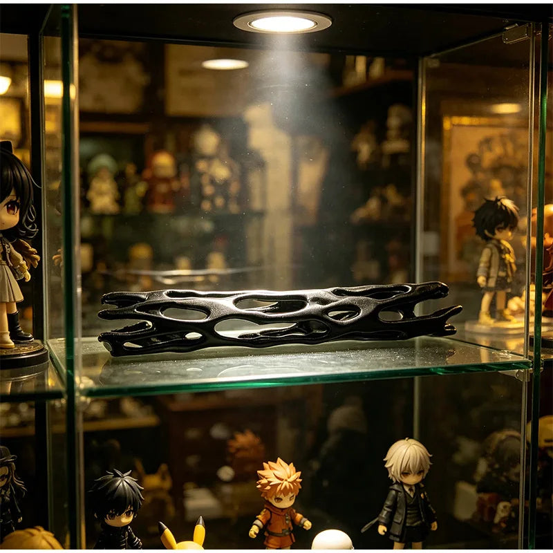 A black willow stick night light projector displayed on a glass shelf among collectible figures.