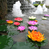 Colorful artificial lotus flowers floating on water with a stone waterfall background