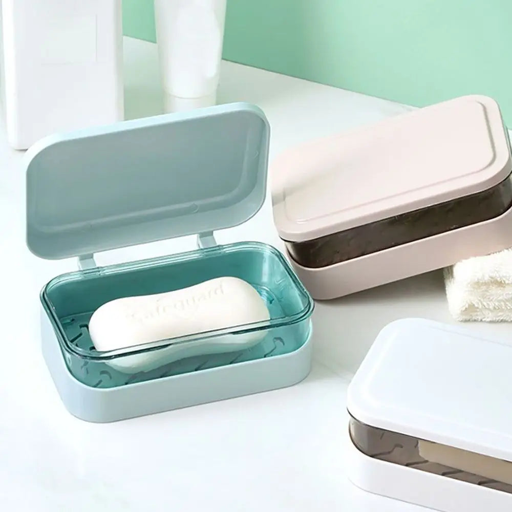 A light blue transparent drainage soap dish holding a white bar of soap on a white surface.