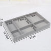 A rectangular gray velvet jewelry organizer tray divided into six compartments with various sized sections.