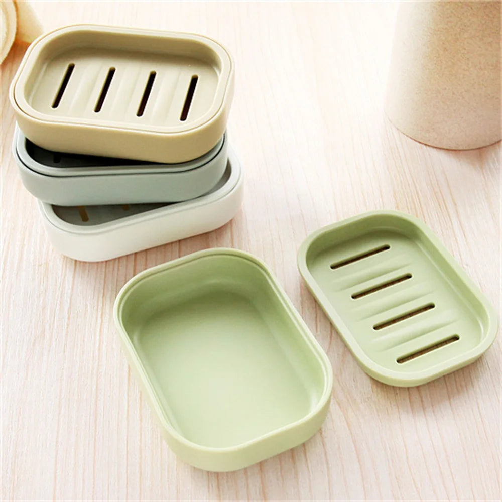 A set of double layer drain soap dishes in light green and beige tones resting on a wooden surface.