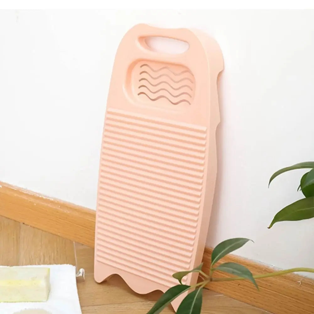 A pink plastic washing board with textured surfaces is shown against a white background.