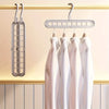 A set of three white plastic hangers hanging on a light-colored wooden rack.