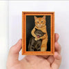 Gerahmtes Gemälde mit zwei Katzen, eine orange und eine schwarz, in einem Holzrahmen.