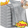 A stack of gray stainless steel wire dish cleaning cloths with one cloth being used to wipe a plate.
