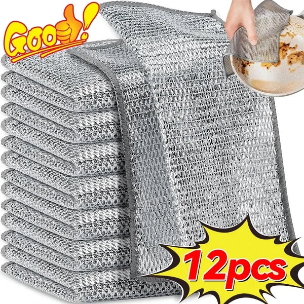A stack of gray stainless steel wire dish cleaning cloths with one cloth being used to wipe a plate.