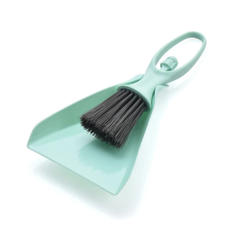 A light mint green mini broom and dustpan set with a handle and bristles for cleaning desks and keyboards.