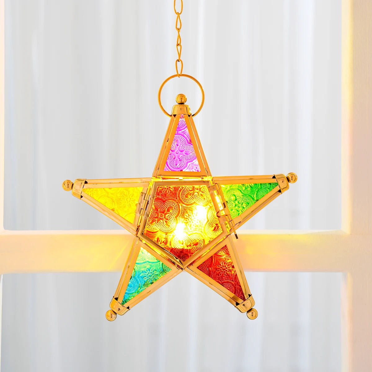 A forged iron star hanging candlestick with stained glass panels emitting a warm glow.