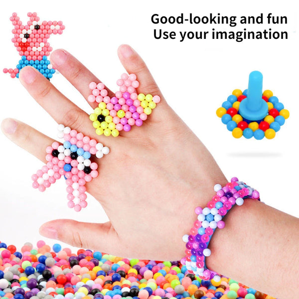 A hand holds several colorful crystal beads, including a pink rabbit figure and a blue figure, demonstrating DIY crafting and