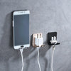 A white aluminum shaving razor storage rack mounted on a gray wall, with charging cables extending from it.