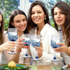 Four women holding blue glass champagne flutes on a wooden table.