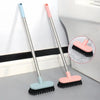 Two long-handle floor scrub brushes in light blue and pink are shown next to a white toilet.
