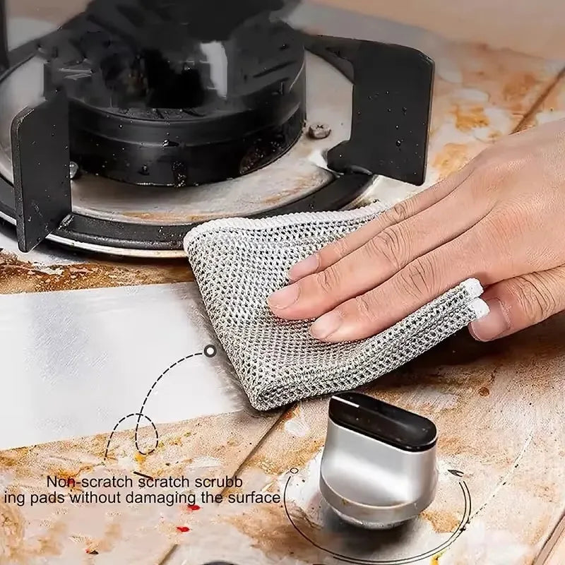 A hand is using a non-scratch scrubbing pad to clean a black appliance surface.