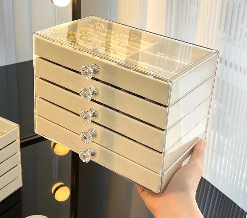 A clear acrylic 5-tier desktop jewelry organizer rack with gold accents is being held by a hand.