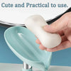 A hand holds a white leaf-shaped suction cup soap holder with a self-draining tray in a light blue bowl.