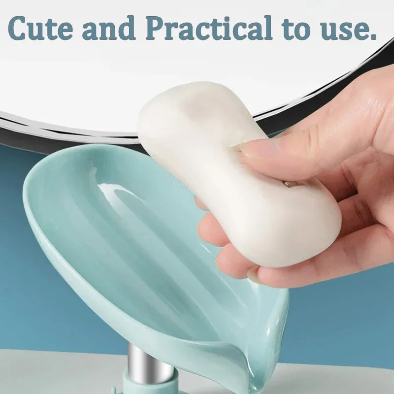 A hand holds a white leaf-shaped suction cup soap holder with a self-draining tray in a light blue bowl.