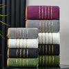 A stack of various colored bath towels, including purple, gray, white, black, and olive green.