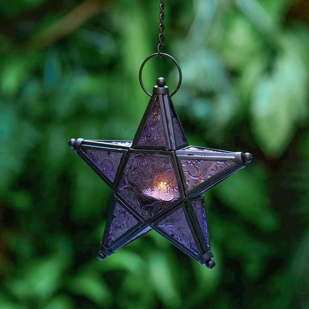 A dark purple forged iron star hanging candlestick with a glowing light, suspended by a metal loop.