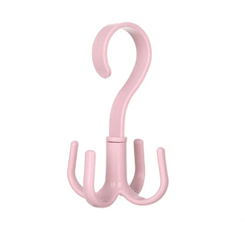 A pink space-saving rotating closet organizer hook with a curved handle and three hanging arms.