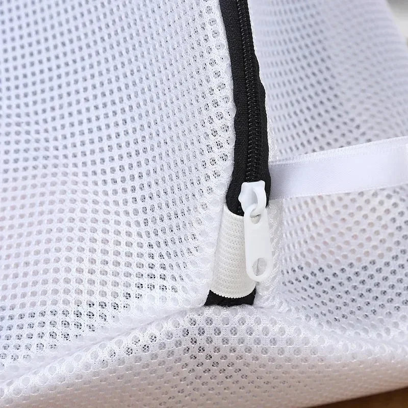 Close-up of a white mesh laundry bag for shoes and delicates showing a black zipper detail.