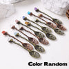 A collection of natural crystal spoons in various colors including purple, blue, and green, arranged on a white surface.