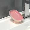 A pink countertop soap dish with a suction cup base is placed on a white sink surface.