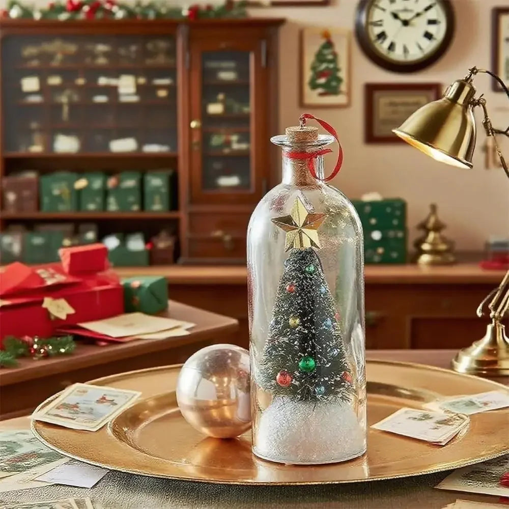 A glass message bottle decorated with a gold star and a festive Christmas tree, resting on a brass plate.