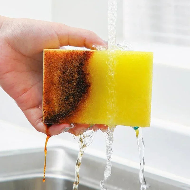 A hand holds a yellow cleaning sponge as water flows over it, showing its texture and use.