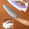 A hand is using a heat resistant ironing pad with a steam iron to press fabric.