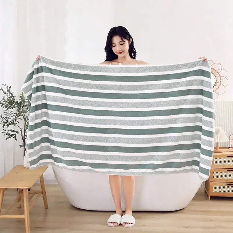 Extra large soft coral fleece bath towel draped over a white bathtub
