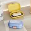 A yellow leakproof travel soap container is shown open, with a closed blue version nearby.