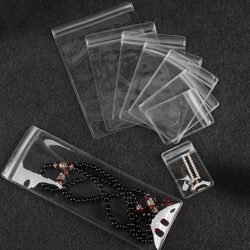 A set of clear PVC zip lock jewelry pouches and a necklace are displayed on a dark surface.