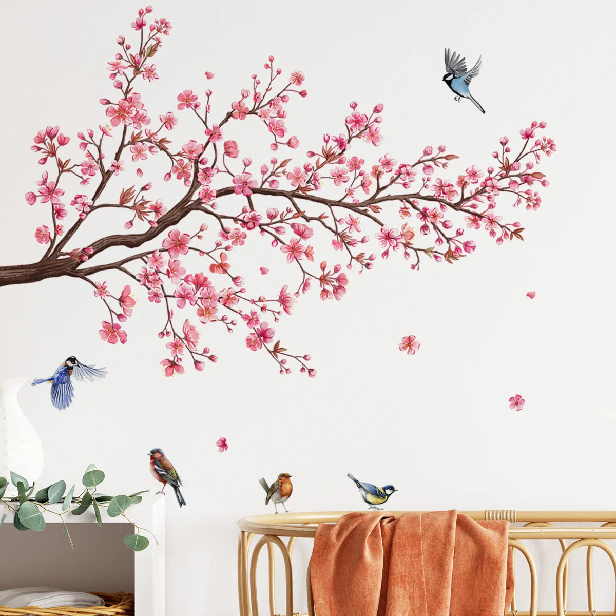 Decorative peach tree branches with pink blossoms and small birds on a white wall.