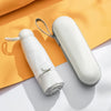 A white mini travel umbrella rolled up, next to its protective sleeve, on an orange background.
