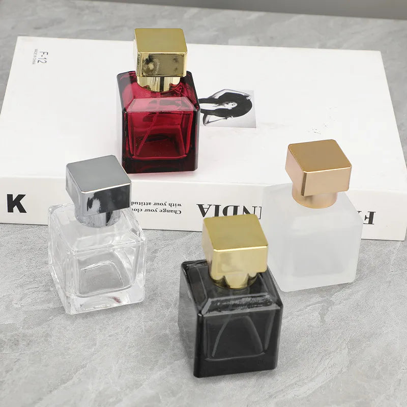 A collection of glass perfume bottles in various colors and shapes, including red, clear, black, and gold accents.