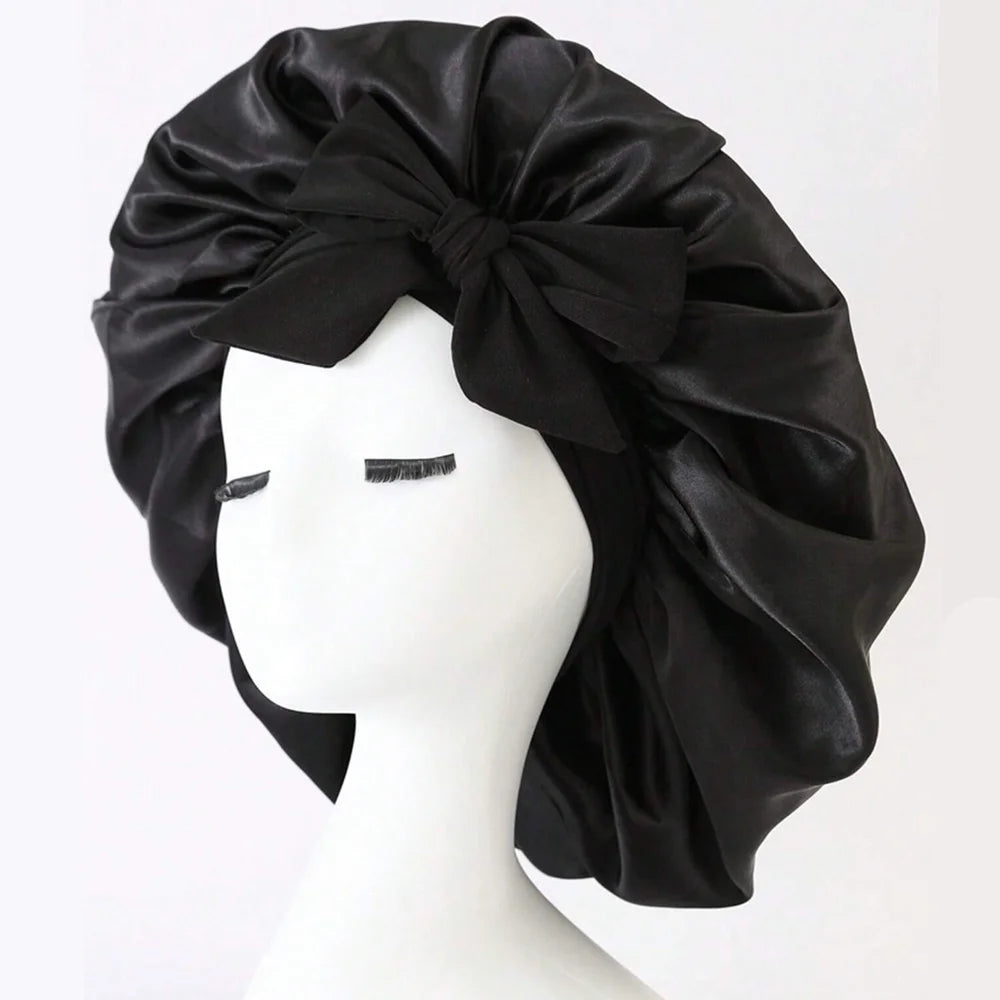 Schwarzer Satin-Seiden-Haube mit Schleife auf weißem Mannequin-Kopf.