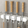 Wall mounted broom holder with wooden handles and chrome rods for kitchen or bathroom