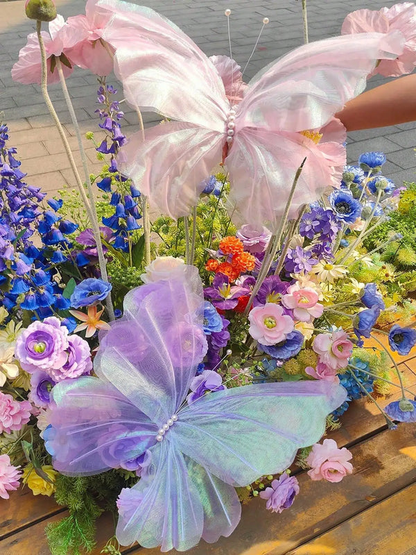 Rosa und lila 3D-simulierte Schmetterlingsdekorationen in einer Blumenanordnung.