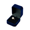 A dark blue velvet jewelry box with an open lid displaying a small silver ring.