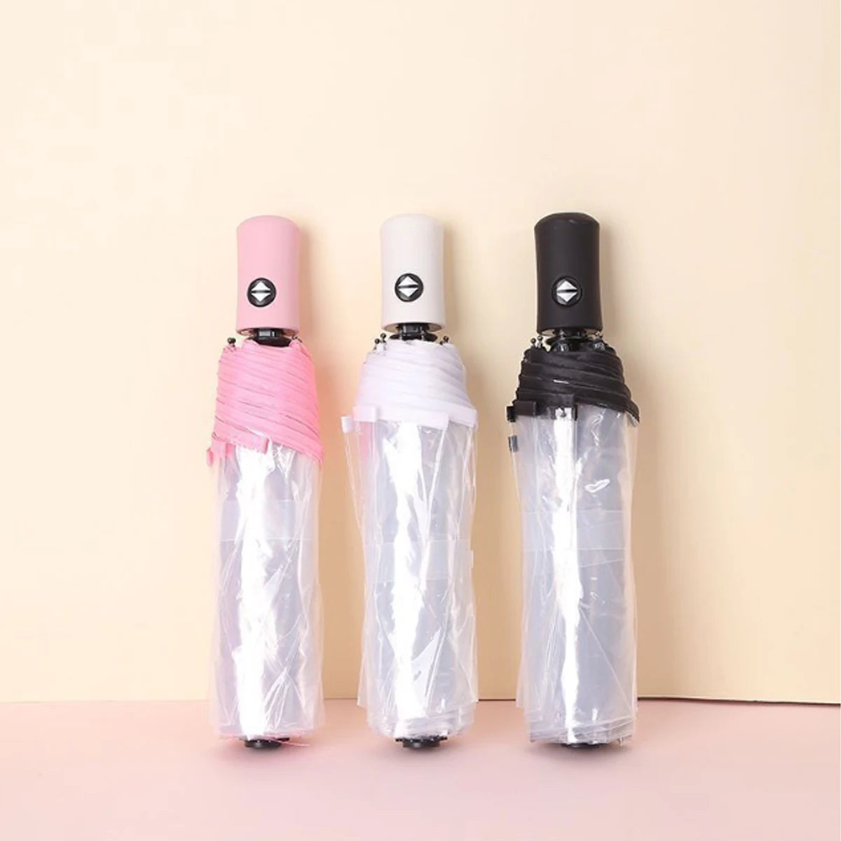 Three automatic transparent folding umbrellas in pink, white, and black are displayed against a light background.