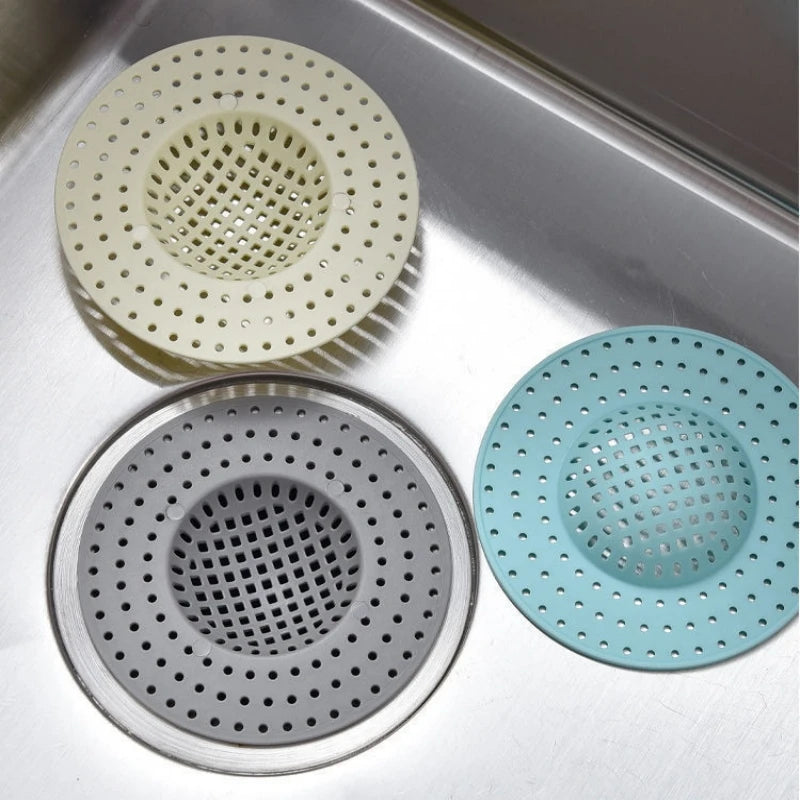 A set of three kitchen sink drain strainers and hair catchers in various shades of light green and gray.