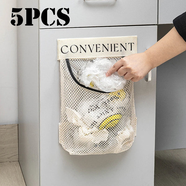 A hand is placing a white elastic mesh bag filled with kitchen items onto a convenient hanging organizer inside a cabinet.