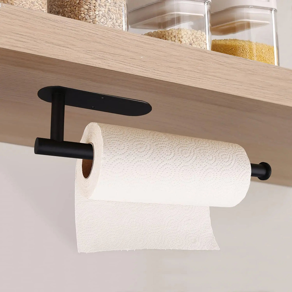 Porta toallas autoadhesivo de acero inoxidable negro montado bajo una estantería de madera, sosteniendo un rollo de toalla bl