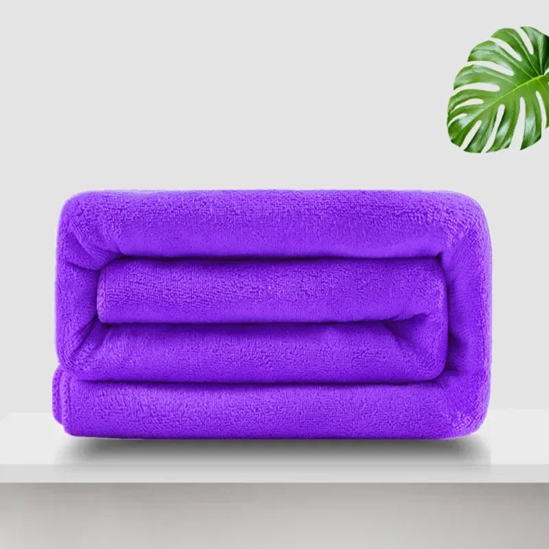 A stack of purple ultra-absorbent microfiber bath towels resting on a white surface.