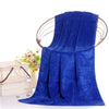 A vibrant royal blue velvet bath towel draped elegantly, with a wooden hanger and flowers in the background.