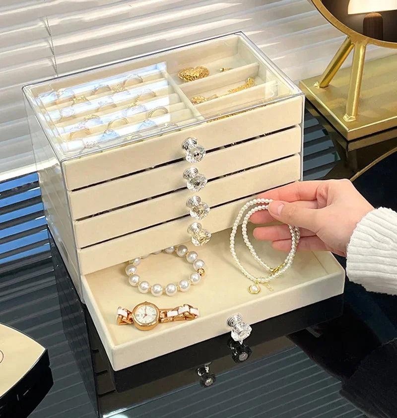 A clear acrylic 5-tier desktop jewelry organizer rack holding various gold and silver bracelets and rings.